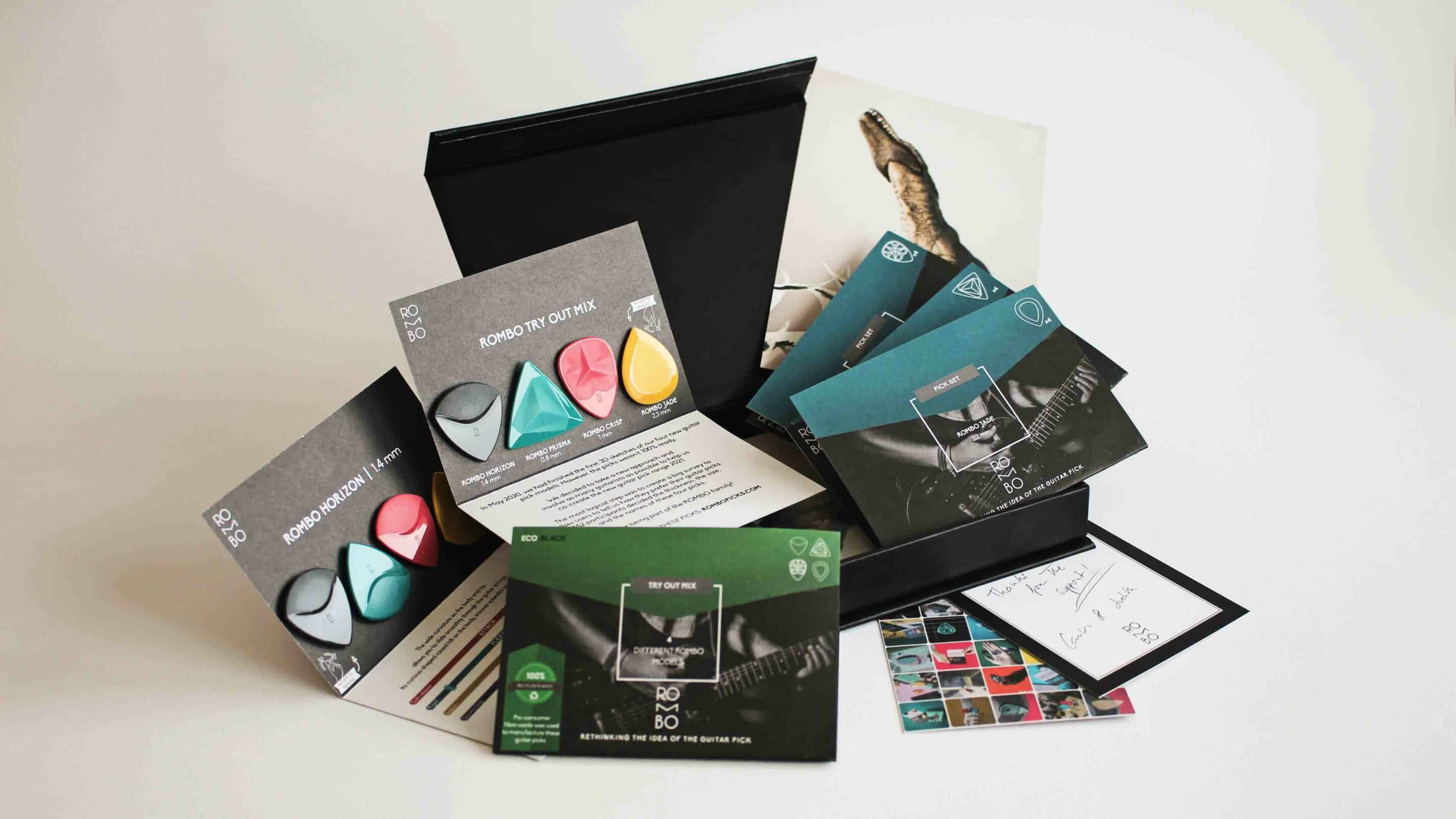 Assorted guitar picks and promotional materials displayed on a white background, showcasing product variety and packaging.